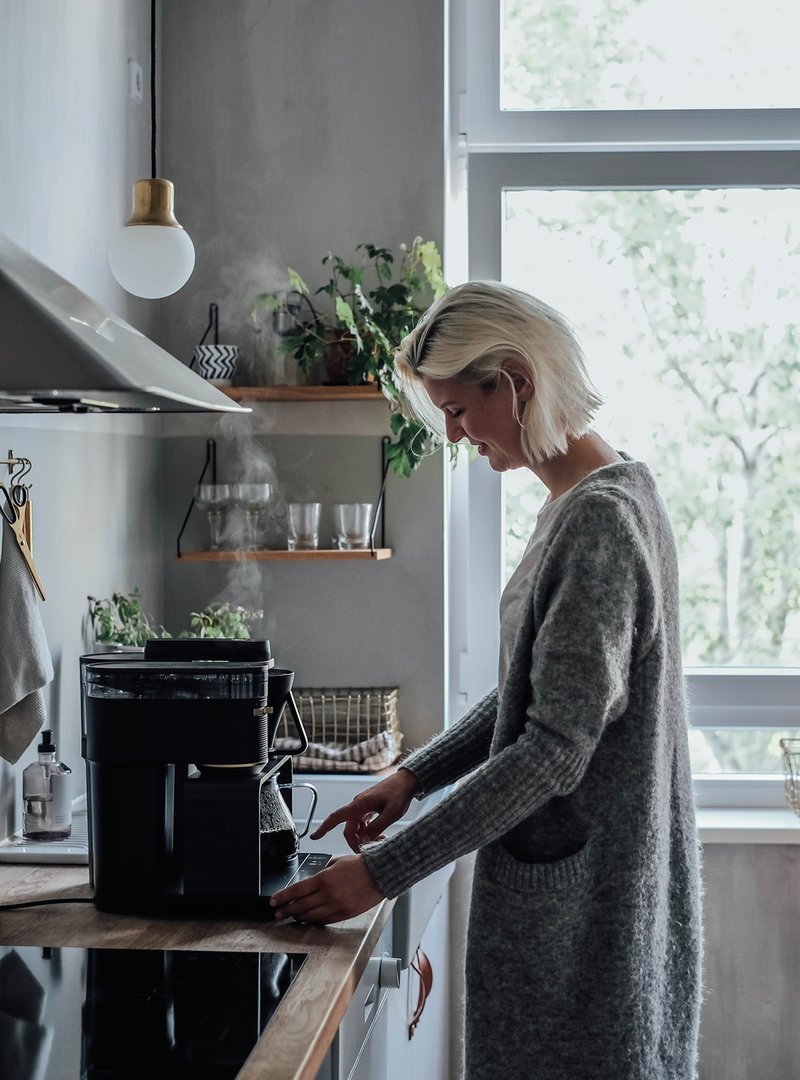 Blonde woman standing in front of the kitchenette with the first electrical Pour Over system by Melitta®.